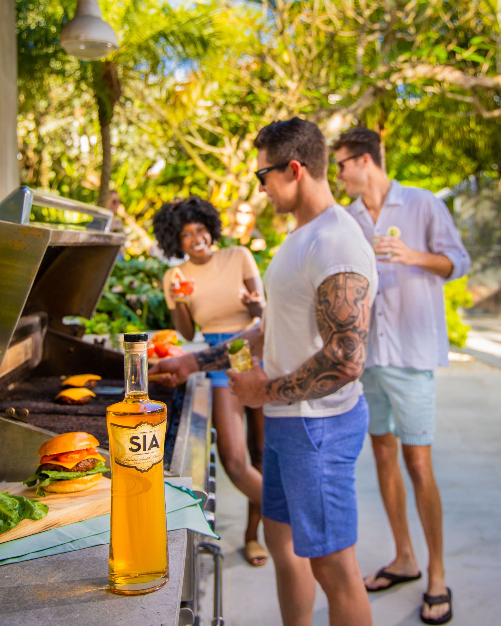 Men and women grilling behind a bottle of SIA Blended Scotch Whisky