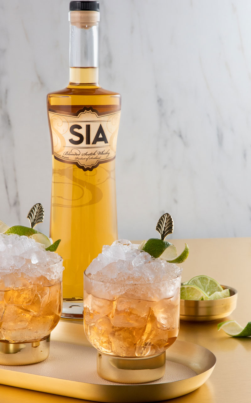 A bottle of SIA Blended Scotch Wisky behind a SIA Glasgow Mule cocktail
