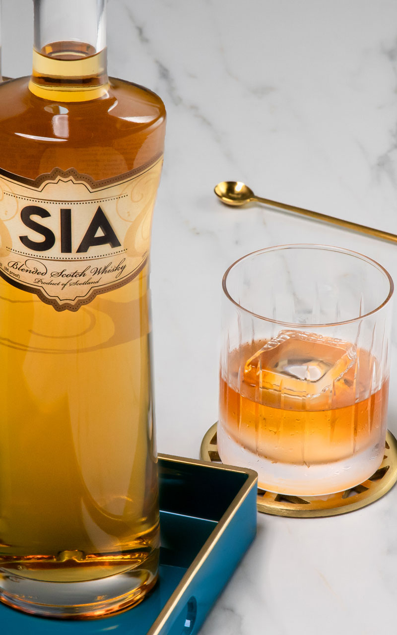 A bottle of SIA Blended Scotch Wisky behind a SIA on the Rocks cocktail